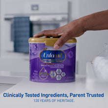 Enfamil Optimum Gentlease formula container on a kitchen counter with a hand reaching for it.